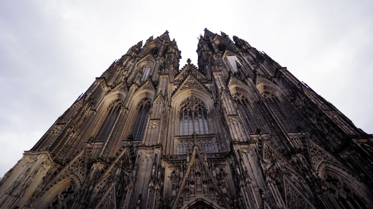 An awe-inspiring upward view of the intricate Gothic facade of Cologne Cathedral, highlighting its towering spires and ornate architectural details.