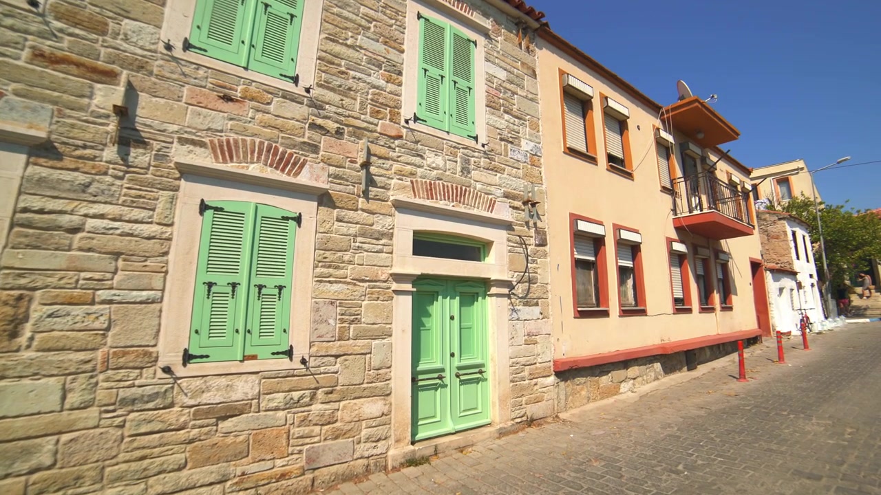 Traditionelles Steinhaus und angrenzendes Gebäude an einer sonnigen Straße
