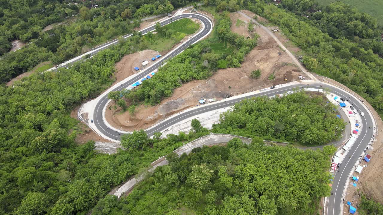 An aerial view showing a winding road through the mountains and forests in the Clongop area, Gunung Kidul, Yogyakarta.