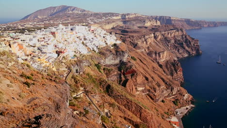 Las-Casas-Se-Alinean-En-Las-Laderas-De-La-Isla-Griega-De-Santorini-Con-Una-Bandera-Griega-En-La-Distancia-1