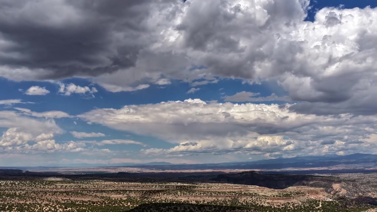 Timelapse 4K UHD con drone: nuvole cumuliformi in rapido movimento proiettano onde dinamiche di ombre su un terreno accidentato di mesa e canyon. Modelli meteorologici mutevoli ad alta quota su un paesaggio desertico.