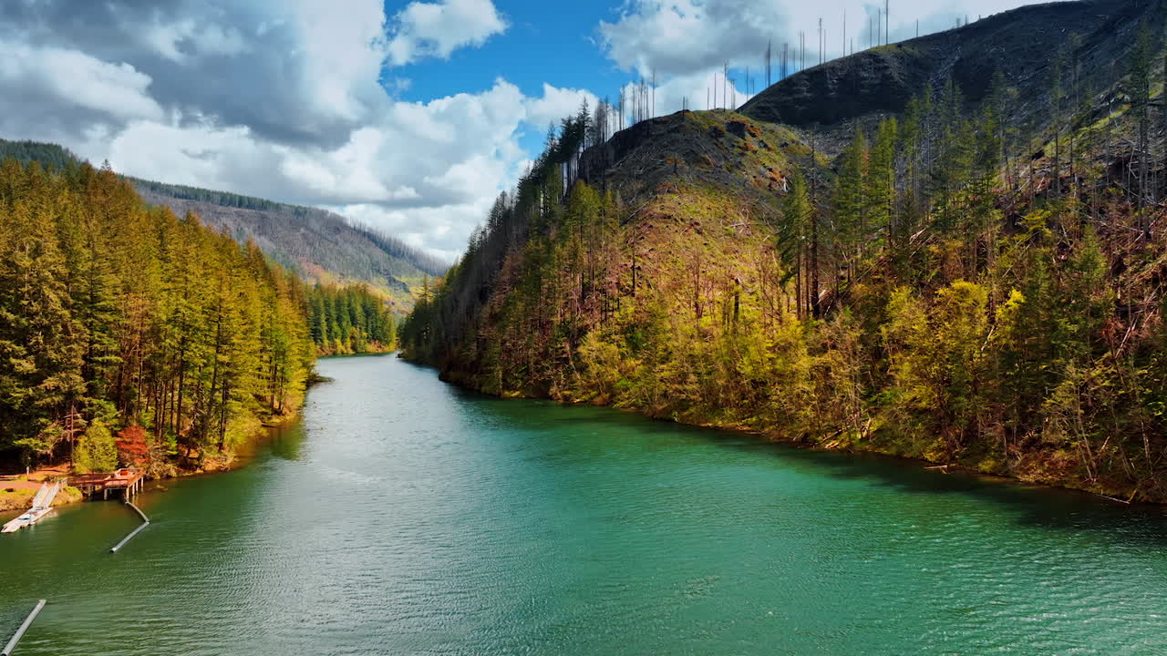 Drone flying low over the beautiful mountain river with sea-blue water. Stunning view of Oregon State wilderness on cloudy day.