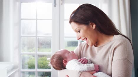 loving mother cuddling sleeping newborn baby boy at home