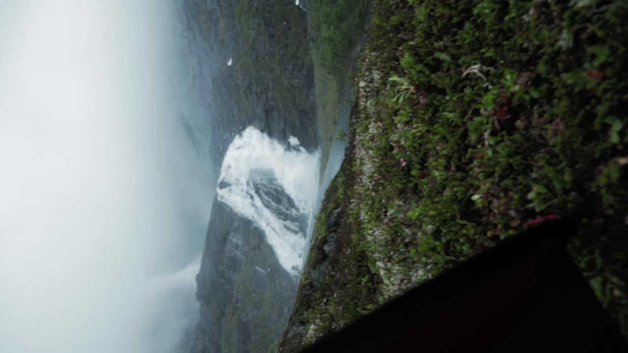 Revealing powerful Husedalen waterfall from inside tent, Norway. Vertical video
