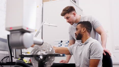 two male engineers uses cmm coordinate measuring machine in factory