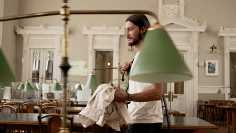 young student walking through library and sitting at the table