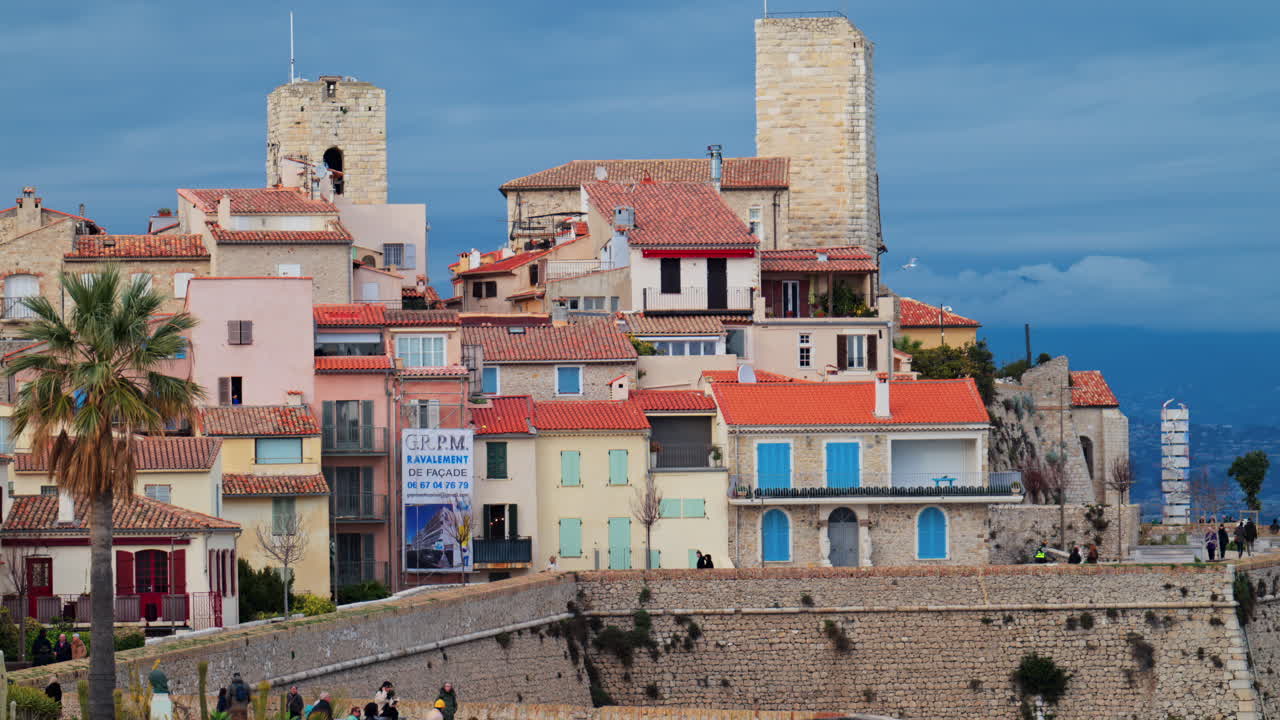Antibes, France - February 20, 2025: Distant view of people walking on the coast near the Picasso Museum Castle