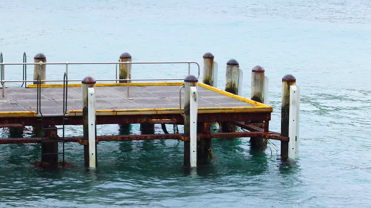 A wooden pier endures rhythmic ocean waves under soft daylight, capturing serene coastal movement