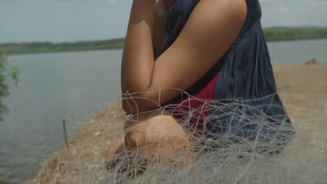 Close-up-of-an-indian-woman-sitting-next-to-fishing-near-on-a-river-looking-at-the-camera