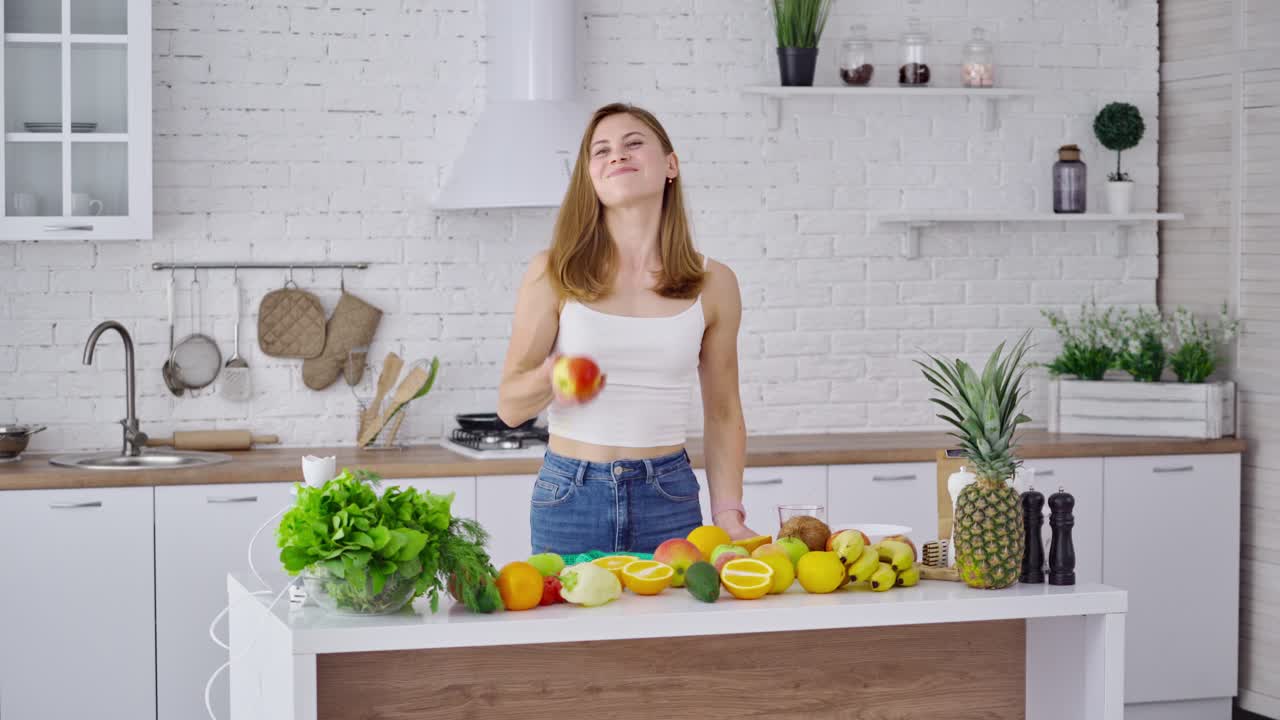 Young woman eating fresh apple. Pretty girl coming to the table with organic fruit and vegetables and taking juicy apple. Healthy food concept.