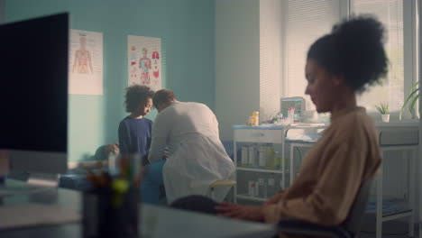madre esperando a su hija en el consultorio del médico. niña africana visita al médico.