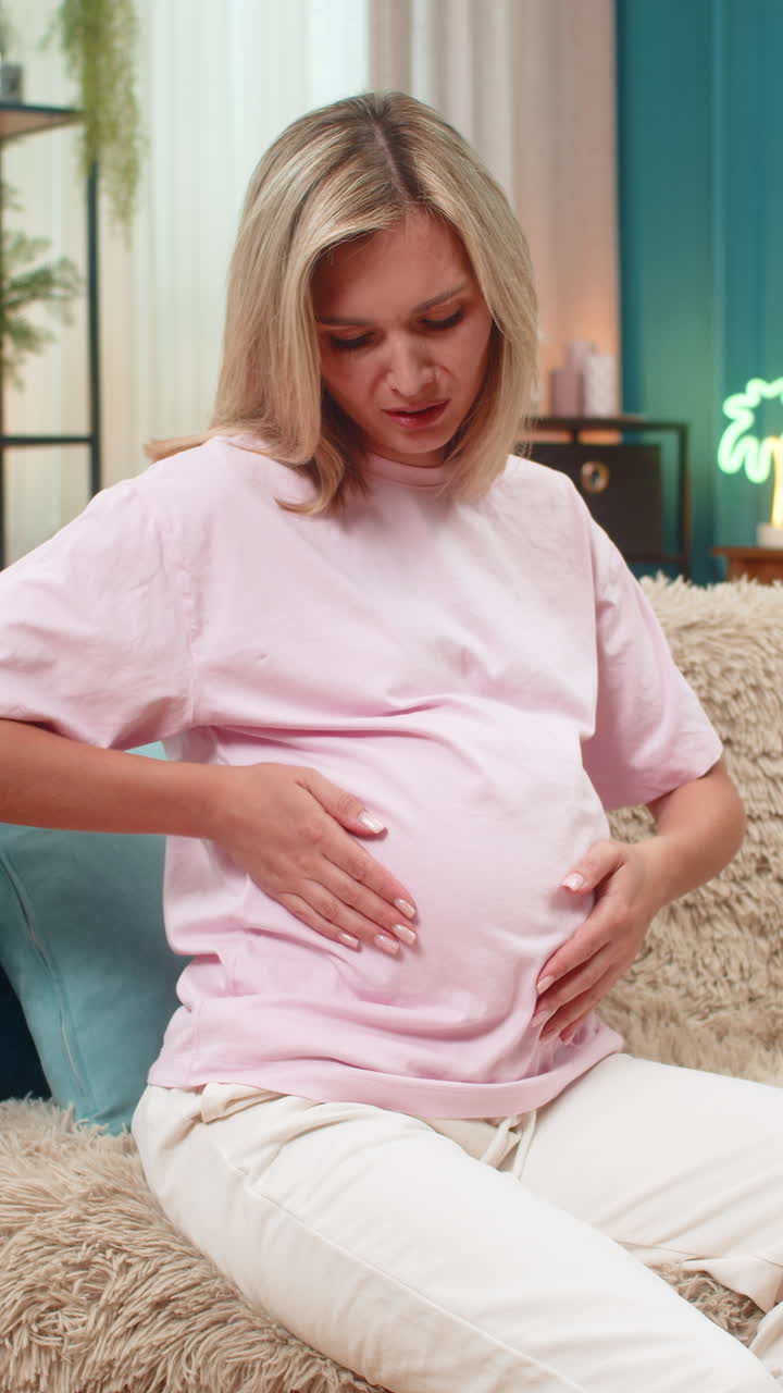 Pregnant woman clutching stomach feeling abdominal pain cramps showing discomfort during pregnancy