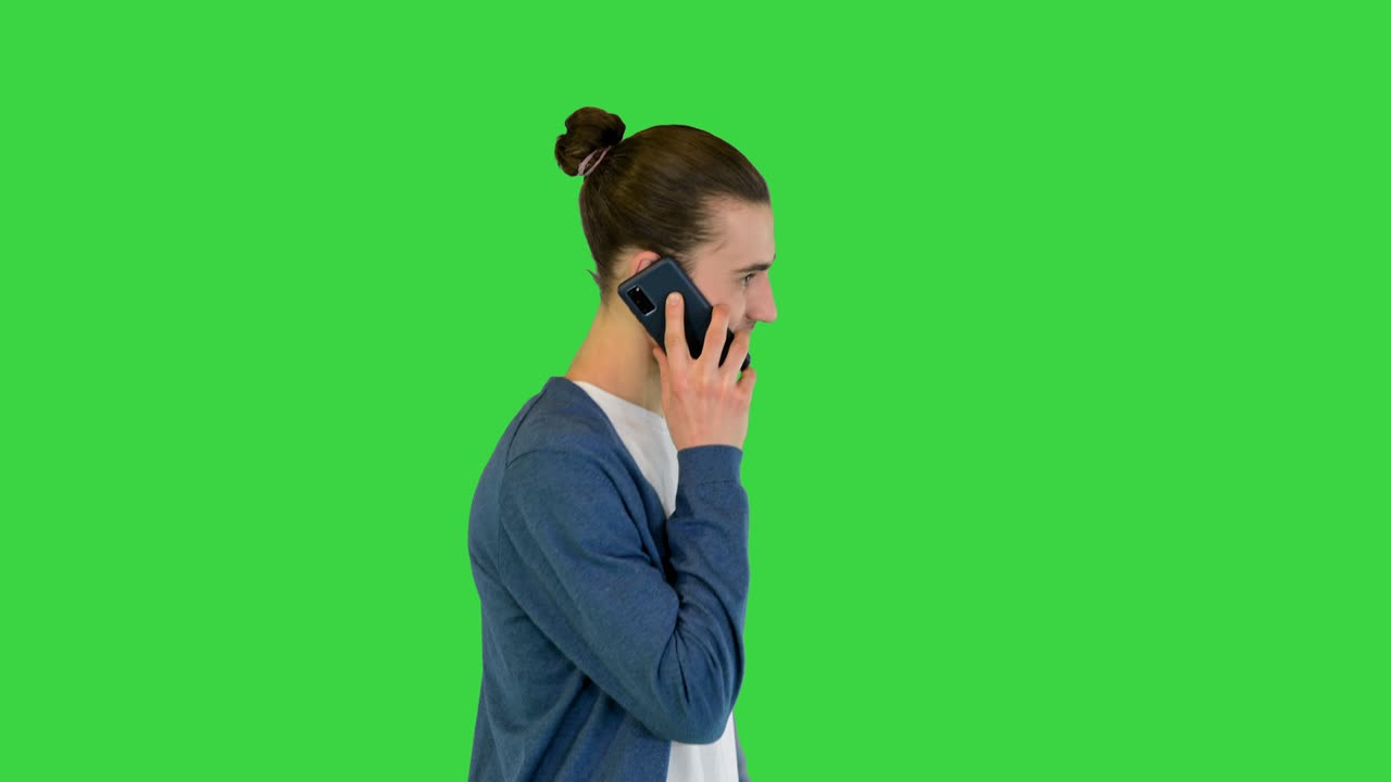 젊은 백인 남자가 스마트폰으로 얘기하고 녹색 화면에서 미소 짓고 걸어가고, 크로마 키