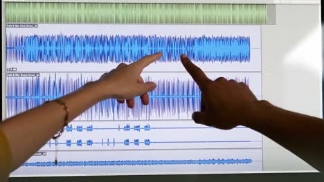 Two-people-pointing-at-music-waves-on-the-screen