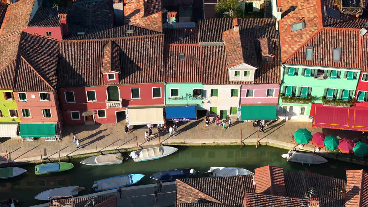 Aerial drone view of boats on the sides of a canal near the colourful houses of Burano island, Italy