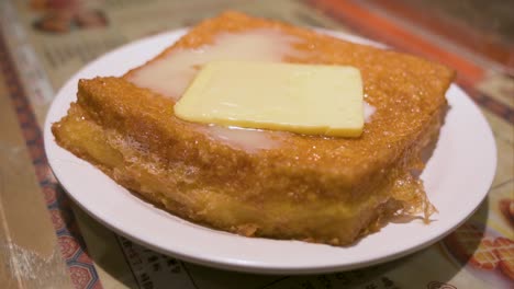 primer plano de una tostada francesa al estilo de hong kong con rebanadas fritas de pan, mantequilla de maní, manteqilla y leche condensada, lista para comer en un restaurante