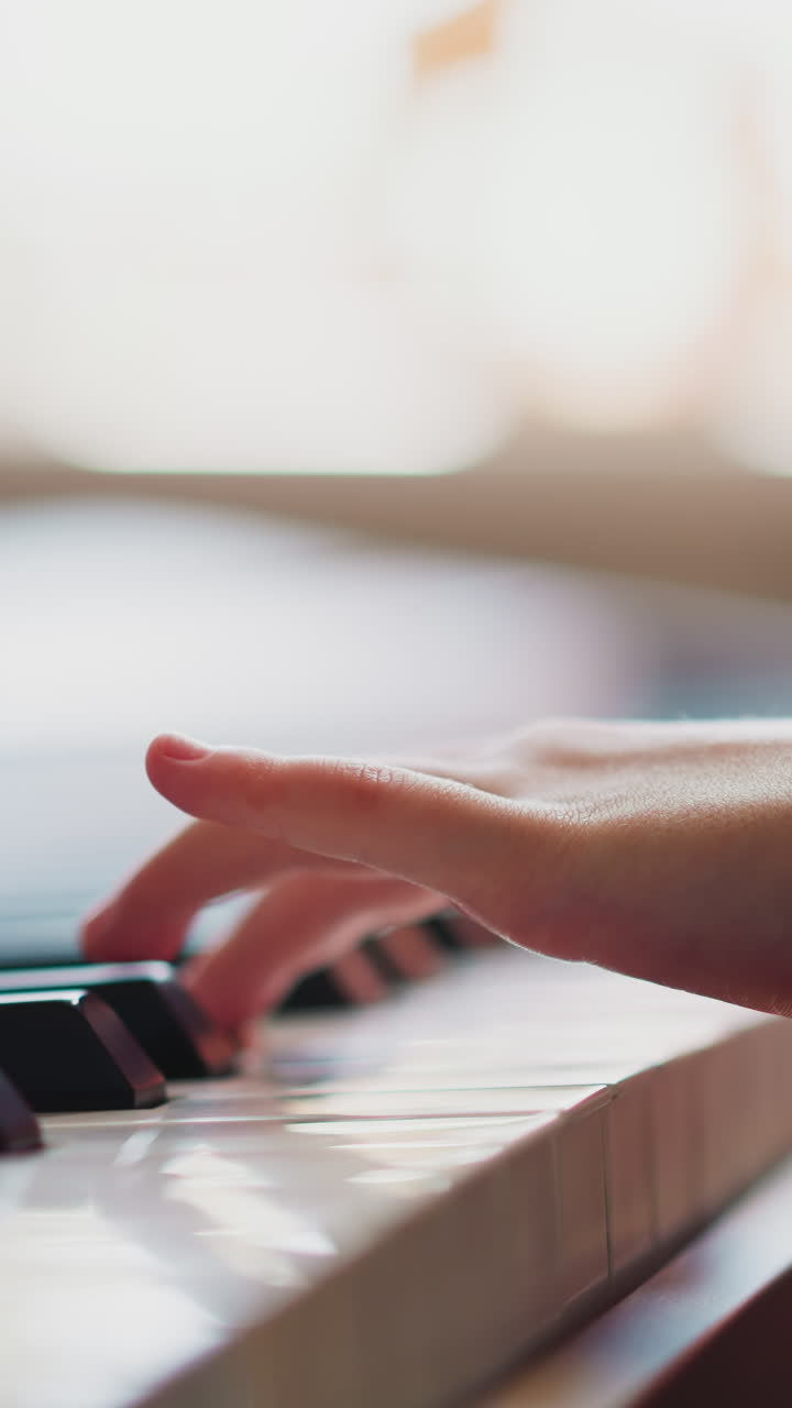 Child hands play piano. Girl with limited mobility learns new melody practicing playing musical instrument in light room. Music education close side view on blurred background