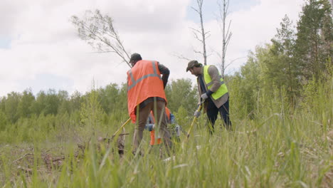 grupo de activistas ecologistas multiétnicos recogiendo malezas en el bosque