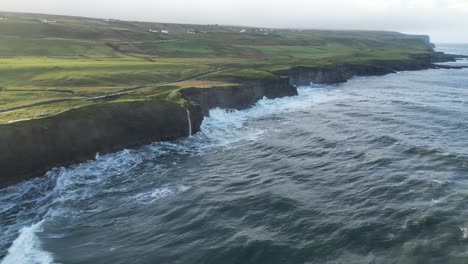 Tiro-Aéreo-Con-Plataforma-Rodante-A-Lo-Largo-Del-Borde-Rocoso-Del-Acantilado-De-Doolin-Con-Olas-Rompiendo