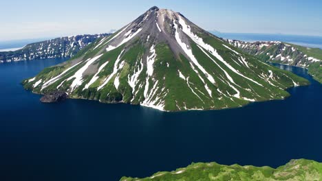 magnífica vista aérea. cono de volcán verde nevado, caldera de agua azul alrededor, soleado