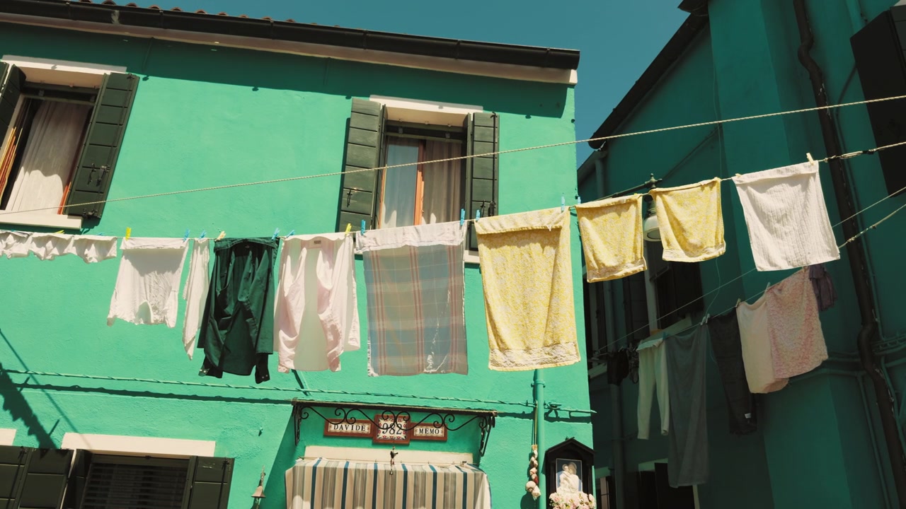 Facciata turchese di una casa di Burano con bucato steso al sole