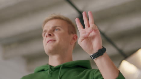 male personal trainer counts down from five using fingers, proudly clap hands