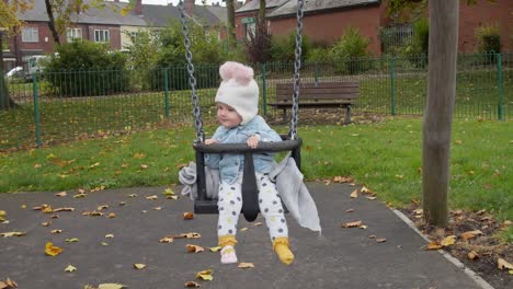 cute child without one shoe having fun with playground swing