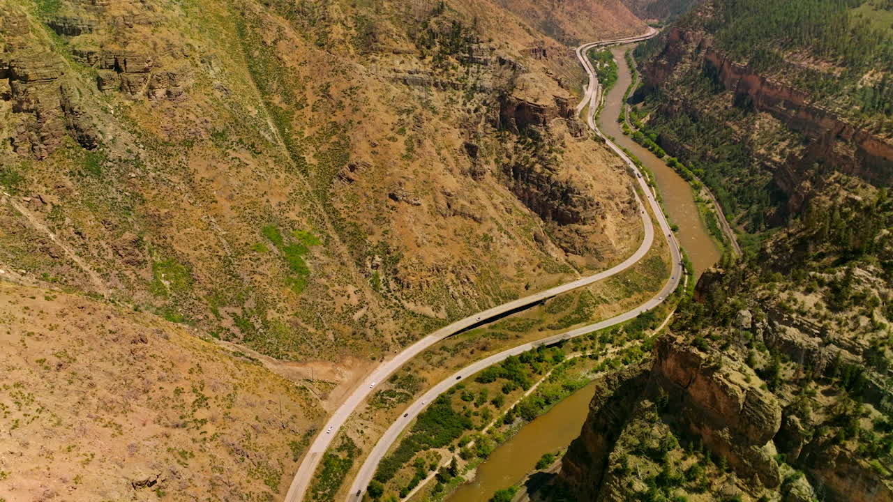 Rocky hills of amazing mountains in Colorado, USA. River flowing at the foot of mountain and roads passing along the river from aerial view.