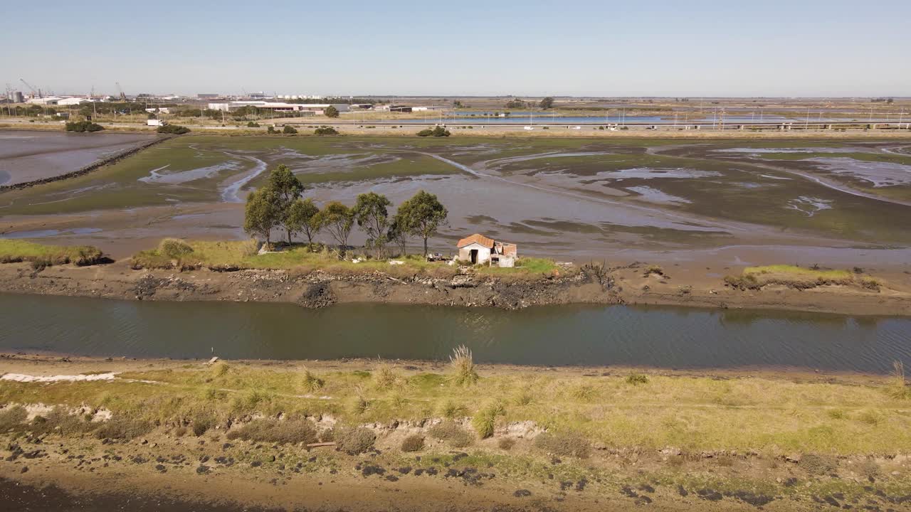 4K luftfoto af et hus midt i nogle kunstige laguner i Ria de Aveiro, med drone der bevæger sig til venstre, 60fps.