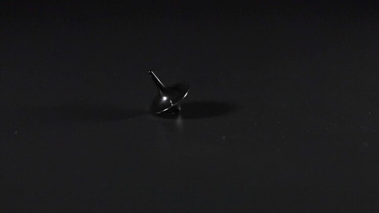 A spinning top rotating on a dark surface
