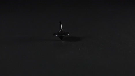 a spinning top rotating on a dark surface