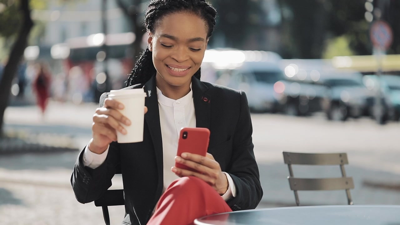 Businesswoman Using Smartphone and Drinking Coffee at Outdoor Cafe