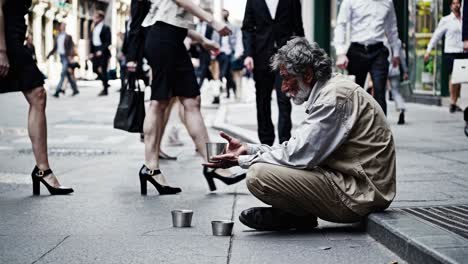 street-level video captures a homeless man sitting on a busy sidewalk, surrounded by blurred