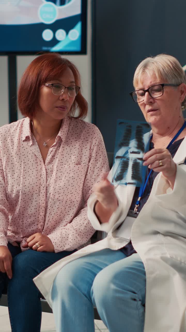 Vertical video: Diverse women looking at bones radiography scan to see diagnosis