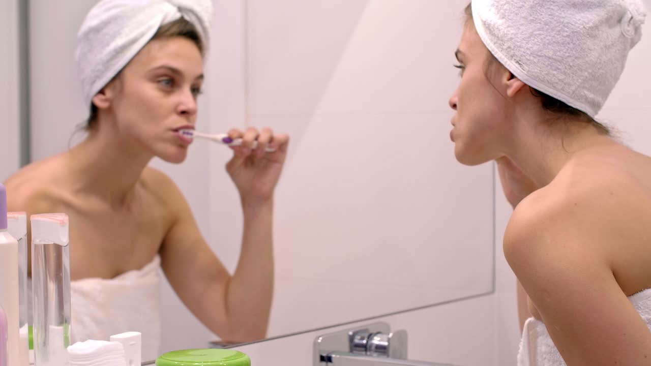 mujer joven cepillándose los dientes en el baño