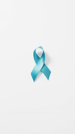 vertical video of pale blue prostate cancer awareness ribbon on white background with copy space