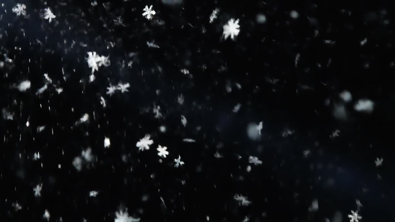 Hvite snøflak faller mot en mørk bakgrunn