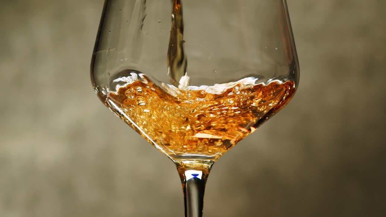 Orange or white wine bottle and glass against a sunset in a peaceful vineyard, pouring of ecological natural wine.