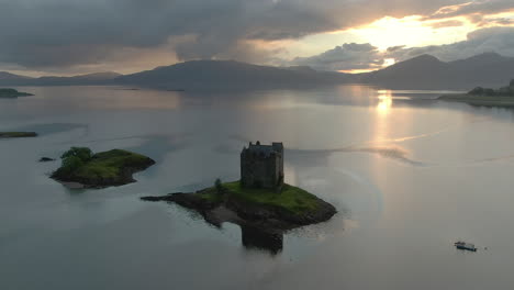 an aerial view of castle stalker on loch laich as the sun begins to set