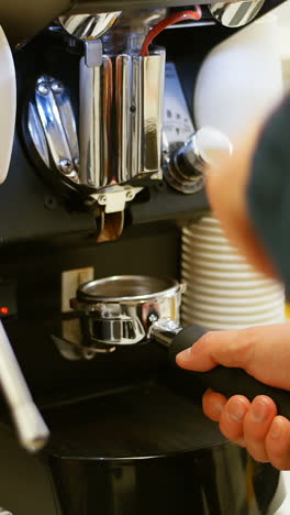 man holding portafilter filled with ground coffee in cafe