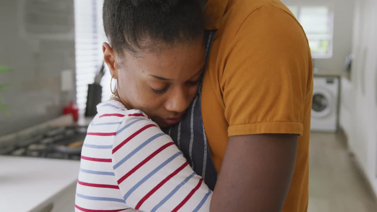 video de una feliz pareja afroamericana abrazándose en la cocina