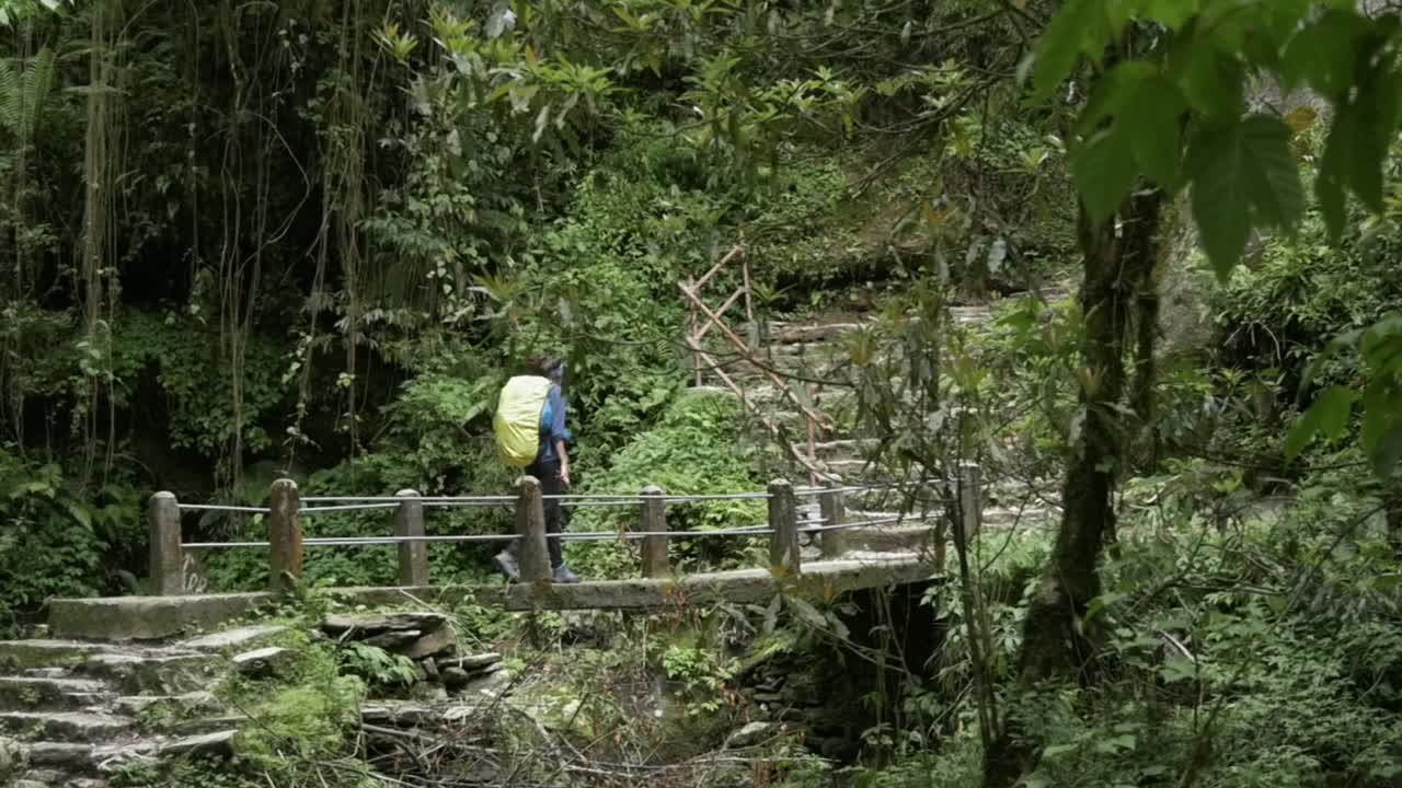 mujer joven caminando por un pequeño puente en nepal, región de annapurna, cámara lenta