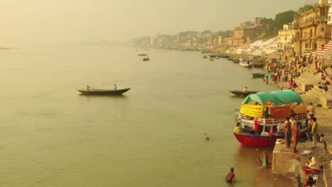 el lapso de tiempo de los peregrinos indios remando en un barco al amanecer. río ganges en varanasi, india.