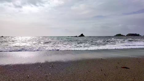 Olas-Espumosas-En-Cámara-Lenta-Rompiendo-Una-Playa-De-Arena-Dorada-En-Waterford,-Irlanda,-En-Primavera