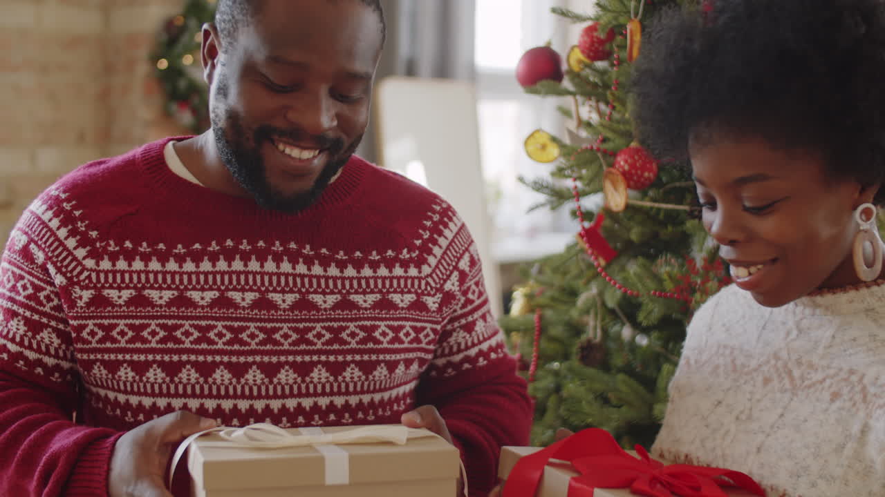 una pareja afroamericana con regalos de navidad y hablando en casa.