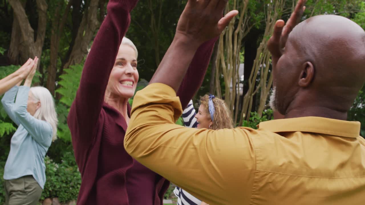 Animation of happy diverse female and male senior friends playing american football in garden