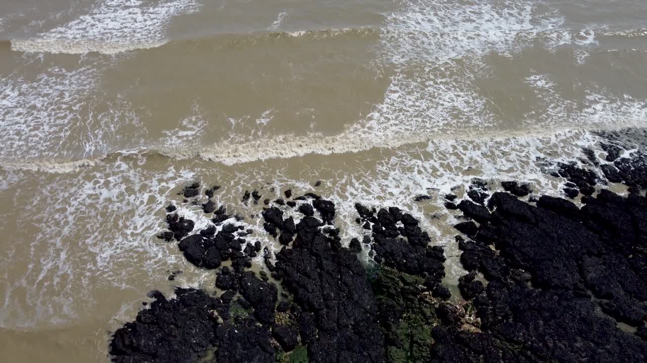 4K drone video of the sea coming into shore over rocks