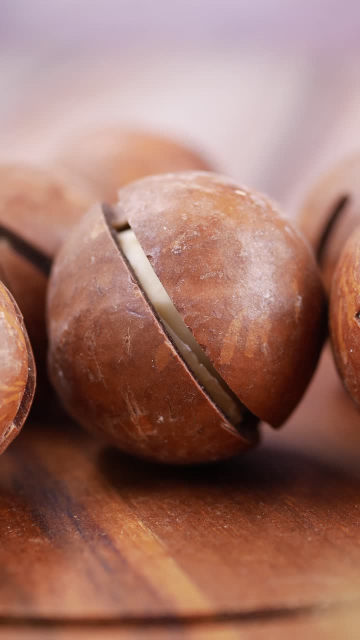 Primo piano di noci di macadamia con gusci rotti su una superficie di legno
