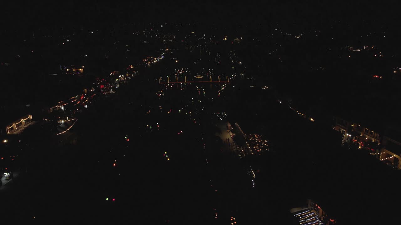 antena nocturna: barcos iluminados navegan por el río de la ciudad oscura en hoi an, vietnam