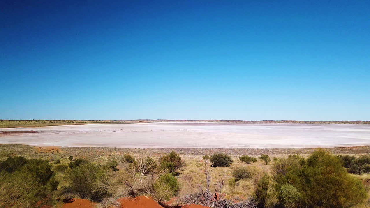 un dron revela un enorme lago salado seco después de volar sobre un remoto sendero de tierra roja en el interior de australia